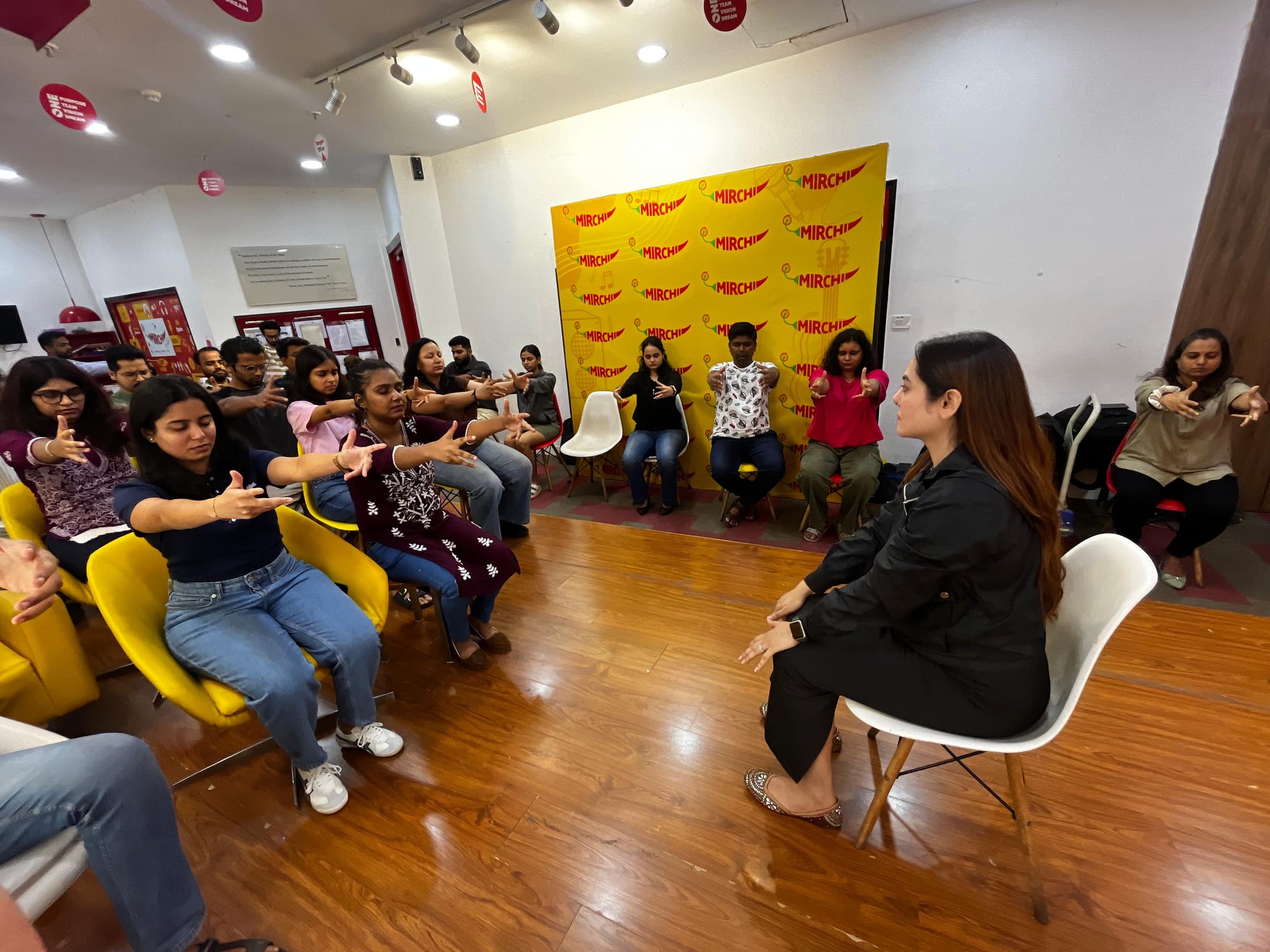 Vibha Jain seated in front of a group during a guided relaxation session, participants following along with their eyes closed.